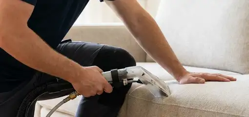 Professional upholstery cleaner deep-cleaning a fabric sofa with a handheld extraction tool, Denver, CO.